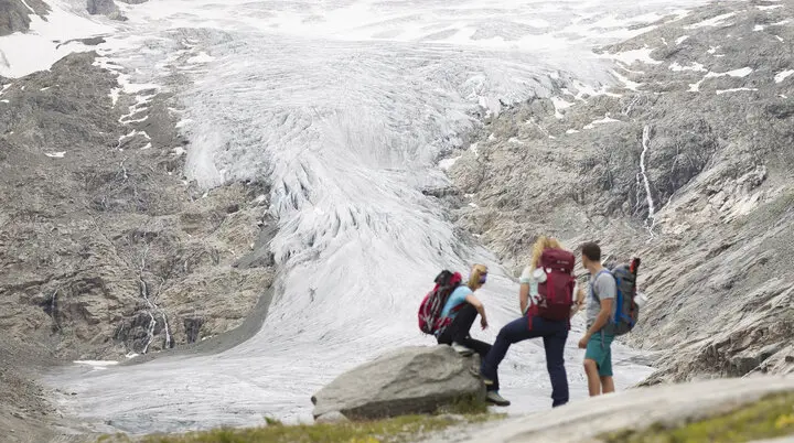 Drei Wandernde blicken nahe der Neuen Prager Hütte am Großvenediger auf den verschwindenden Gletscher. | © DAV / Jens Klatt