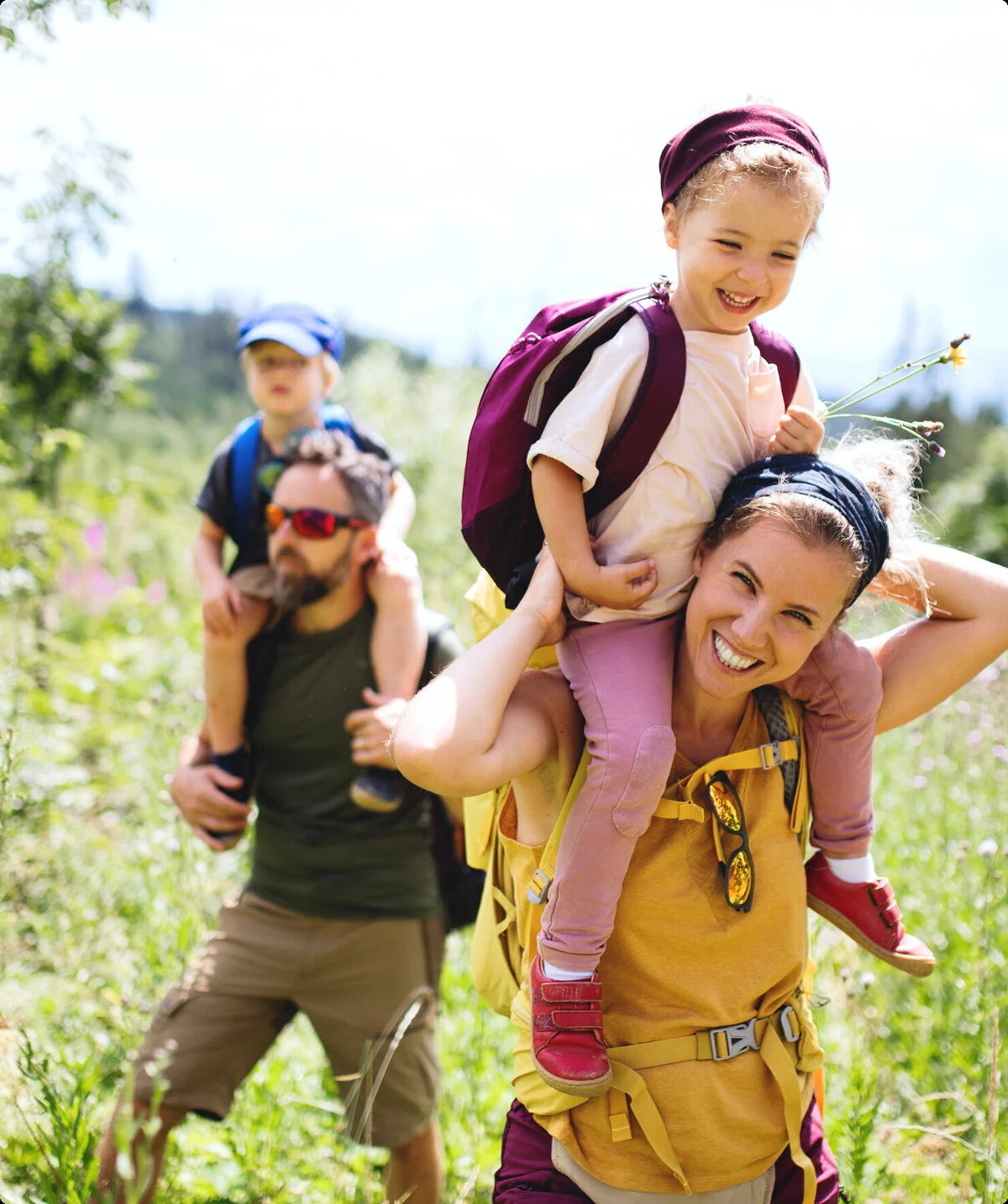 Eine Familie in der Natur, die Mutter trägt ein Kind auf den Schultern | © Halfpoint / Adobe Stock
